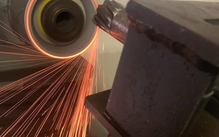 Sparks flying as a cutter is ground against the wheel in the Helix Industrial Sharpening workshop