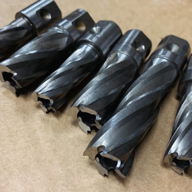 Six sharpened annular cutters laid out in a row
