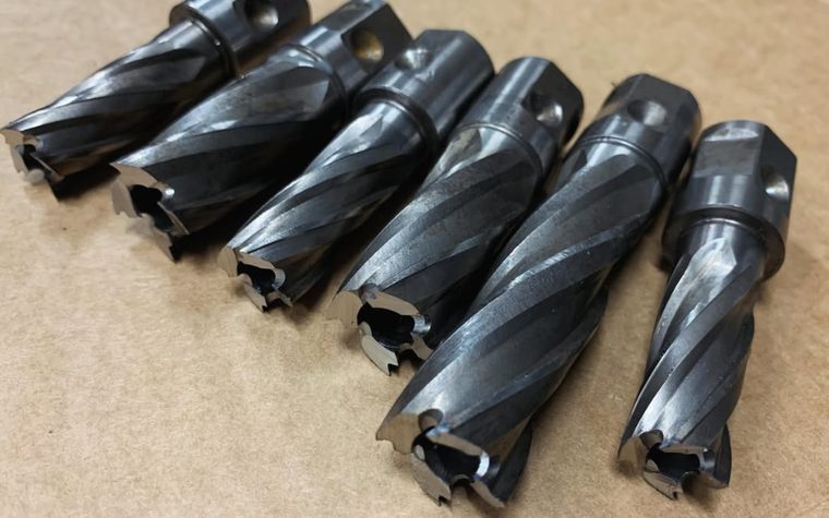 Six sharpened annular cutters laid out in a row