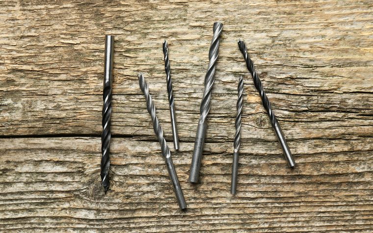 A set of sharpened drill bits laid out on a workbench